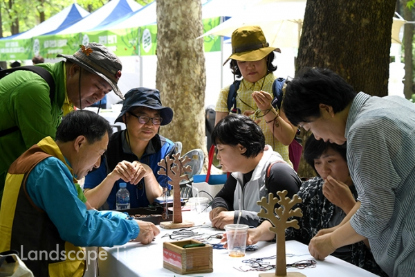 '숲으로 가자' 행사 참가자들이 나무를 활용한 목걸이 만들기 체험을 하고 있다. [제공 : 산림청]