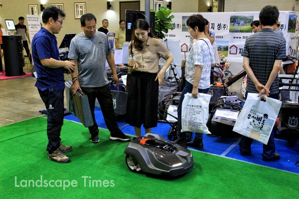 혼자 웅웅 거리며 잔디를 깎는 잔디깎기 로봇에 관심을 보이고 있는 관람객들. [사진 지재호 기자]