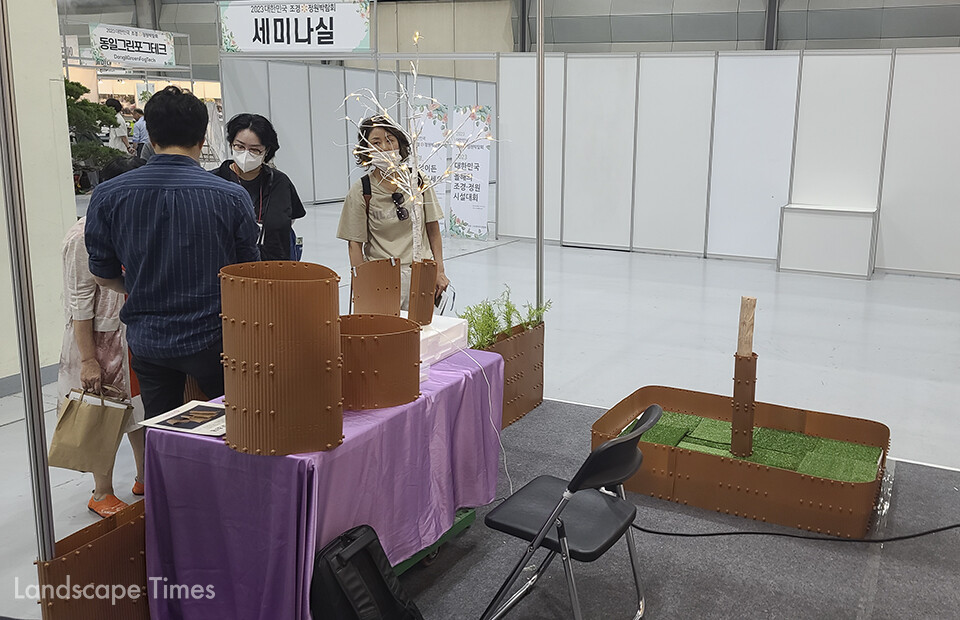 한국조경신문 부스에 마련된 티알프로 다목적 수목보호대 제품들과 관람객들